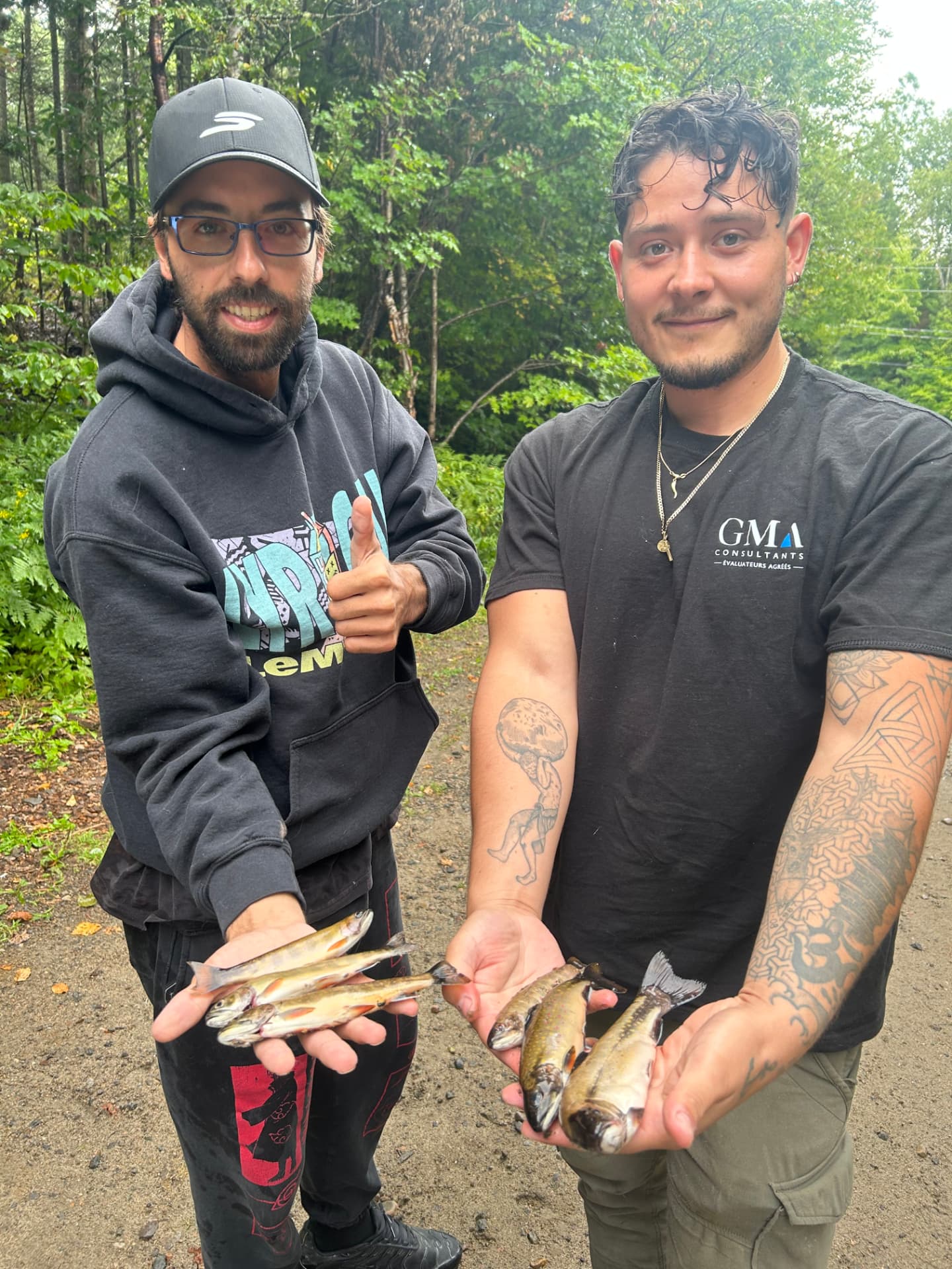 Deux pêcheurs souriants montrant leurs truites mouchetées après une sortie guidée dans les Laurentides